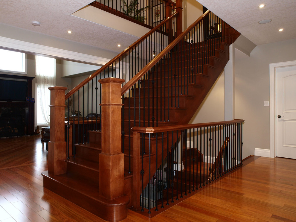 This is an example of a mid-sized transitional wood straight staircase in Toronto with wood risers and metal railing.