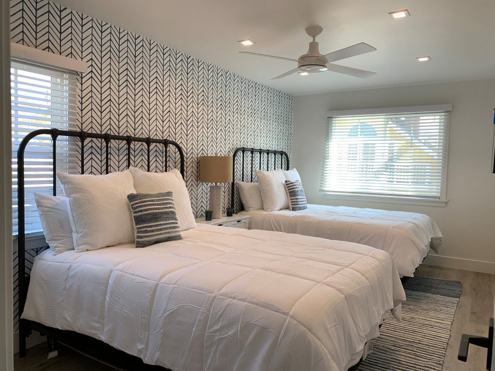 Diseño de habitación de invitados costera pequeña con paredes azules, suelo vinílico, suelo beige y papel pintado