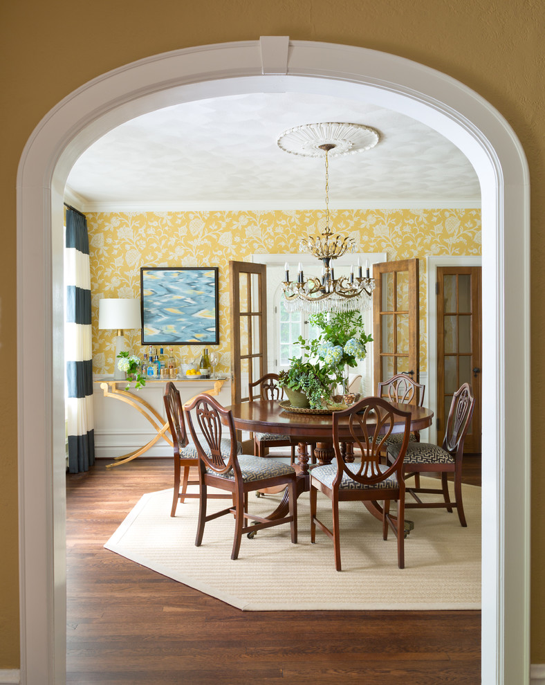 This is an example of a large traditional separate dining room in St Louis with yellow walls and dark hardwood floors.