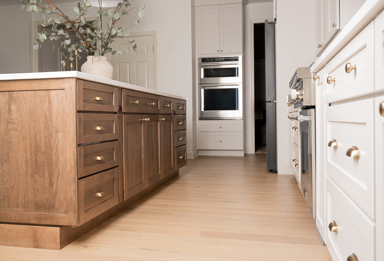 Large transitional u-shaped light wood floor, brown floor and vaulted ceiling eat-in kitchen photo with an undermount sink, shaker cabinets, white cabinets, quartz countertops, white backsplash, porcelain backsplash, stainless steel appliances, an island and white countertops