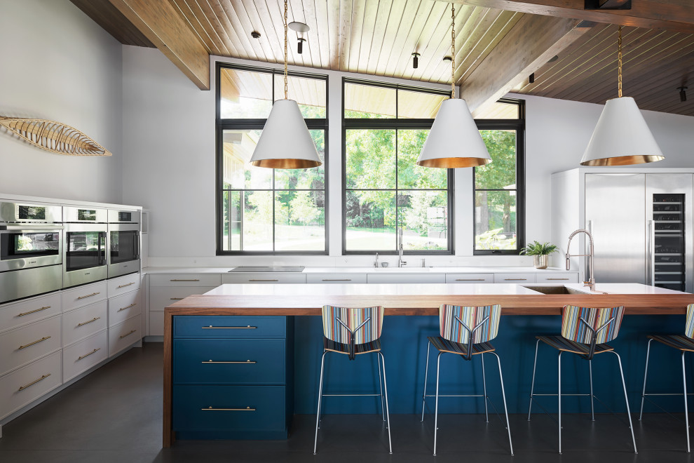 Photo of an expansive contemporary kitchen in Grand Rapids with a farmhouse sink, blue cabinets, stainless steel appliances, concrete floors, with island, grey floor and white benchtop.