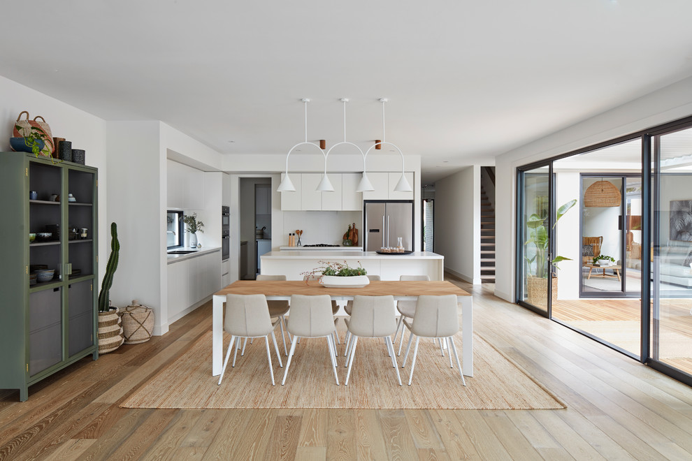 Contemporary open plan dining in Melbourne with white walls, light hardwood floors and brown floor.