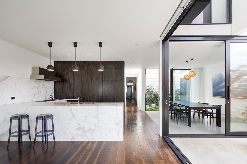 This is an example of a mid-sized contemporary l-shaped eat-in kitchen in Melbourne with an undermount sink, dark wood cabinets, marble benchtops, white splashback, stainless steel appliances, dark hardwood floors and a peninsula.