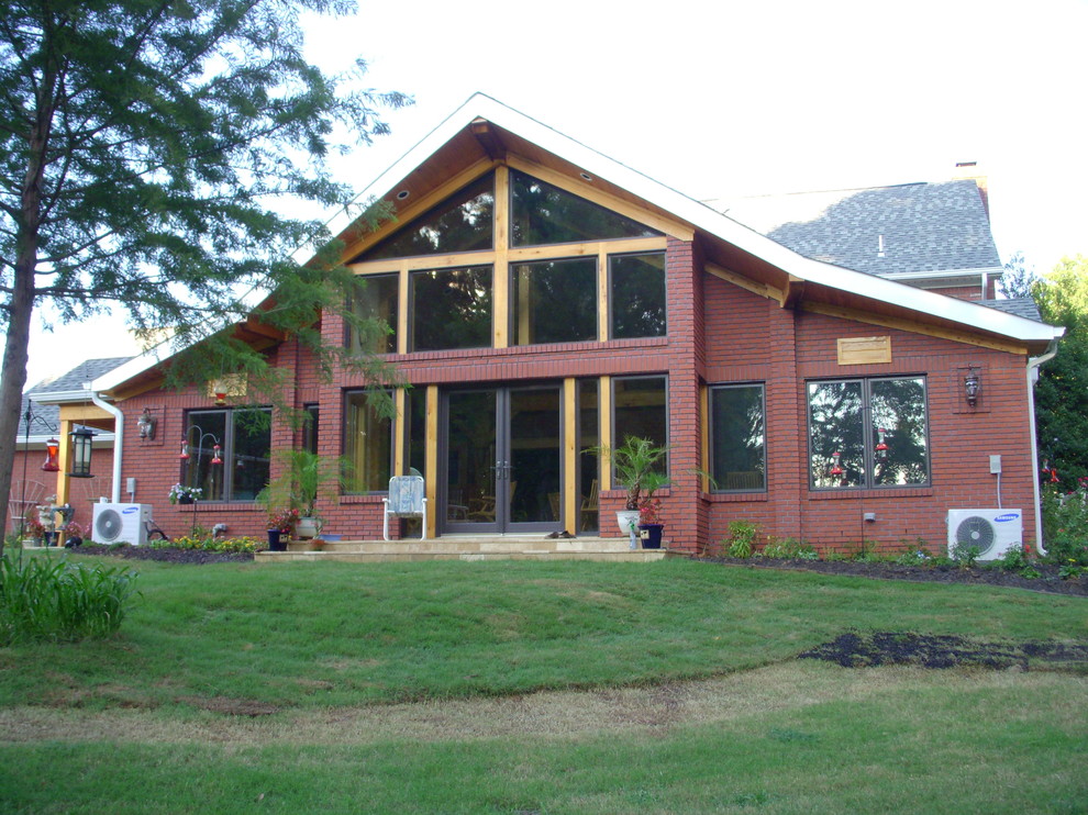 Immagine della facciata di una casa grande rossa classica a due piani con rivestimento in mattoni e falda a timpano