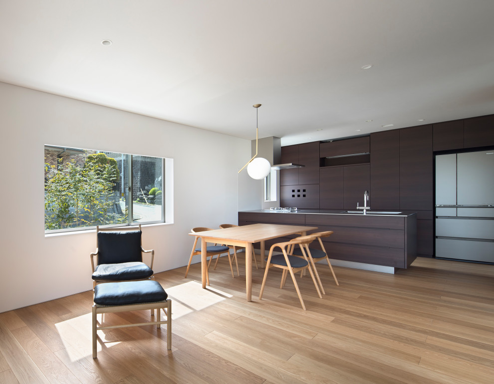 Photo of a mid-sized modern single-wall open plan kitchen in Fukuoka with an integrated sink, flat-panel cabinets, dark wood cabinets, stainless steel benchtops, black splashback, timber splashback, stainless steel appliances, with island, beige floor, wallpaper and light hardwood floors.