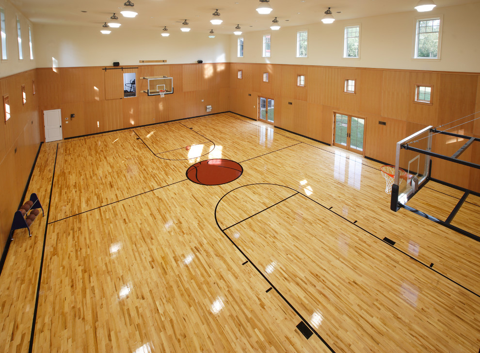 This is an example of a large indoor sport court in Boston with beige walls and light hardwood floors.