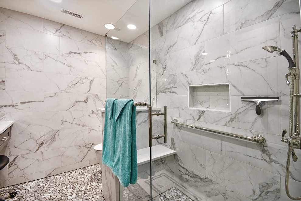 На фото: маленькая главная ванная комната в современном стиле с фасадами в стиле шейкер, серыми фасадами, угловым душем, унитазом-моноблоком, белой плиткой, керамогранитной плиткой, белыми стенами, полом из галечной плитки, врезной раковиной, столешницей из искусственного кварца, серым полом, душем с распашными дверями, белой столешницей, сиденьем для душа, тумбой под одну раковину и встроенной тумбой для на участке и в саду с