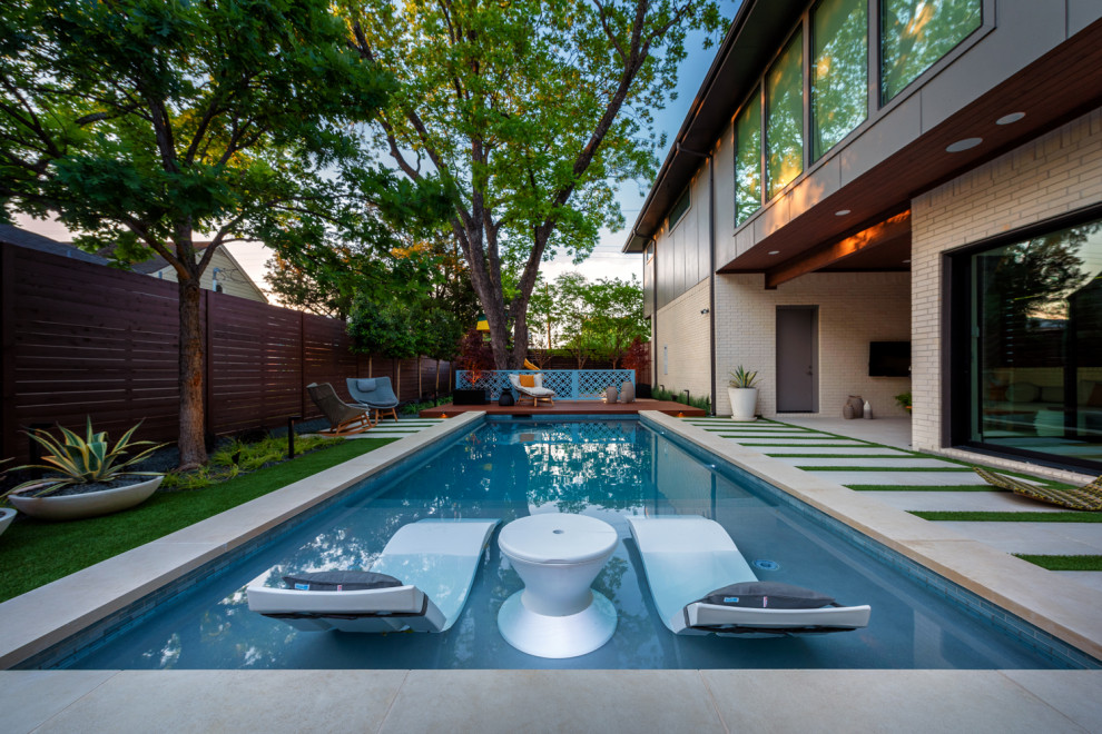 Photo of a mid-sized contemporary backyard rectangular pool in Dallas with natural stone pavers.