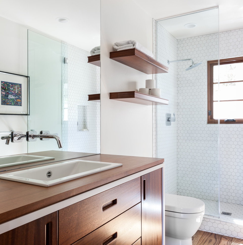 Design ideas for a mediterranean bathroom in Sacramento with beaded inset cabinets, medium wood cabinets, an alcove shower, a one-piece toilet, white tile, white walls, medium hardwood floors, a drop-in sink, wood benchtops, brown floor, a hinged shower door and brown benchtops.