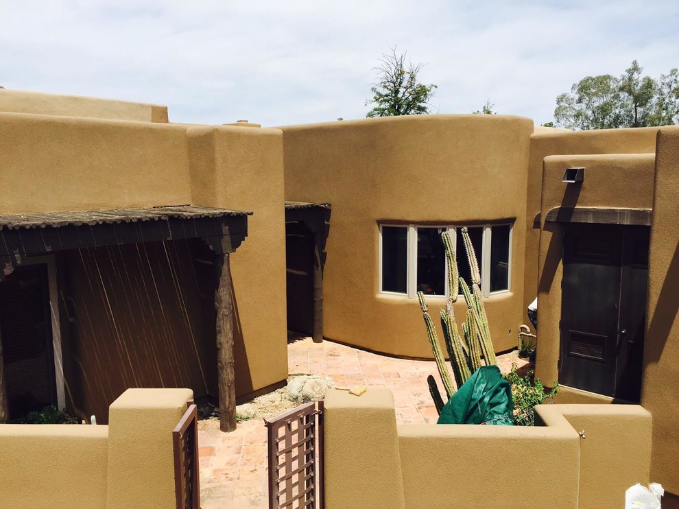 This is an example of a mid-sized one-storey stucco brown house exterior in Phoenix with a flat roof.