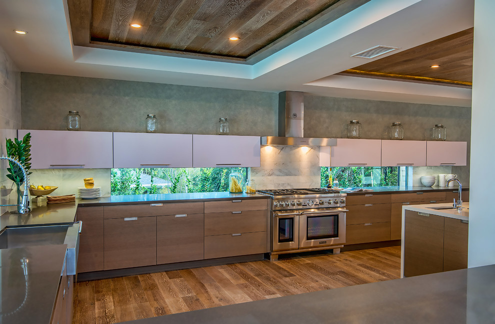 Large contemporary u-shaped kitchen in Los Angeles with a farmhouse sink, flat-panel cabinets, brown cabinets, quartz benchtops, grey splashback, stone slab splashback, stainless steel appliances, medium hardwood floors and with island.