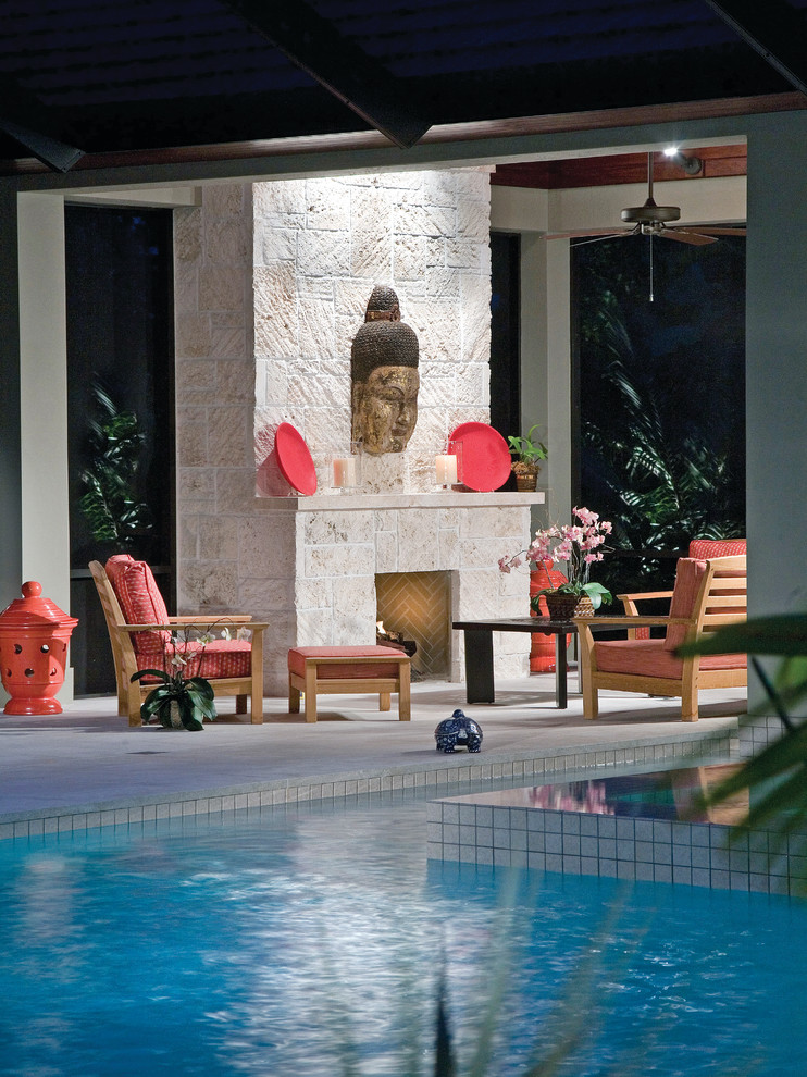 This is an example of an asian backyard custom-shaped pool in Miami with natural stone pavers.