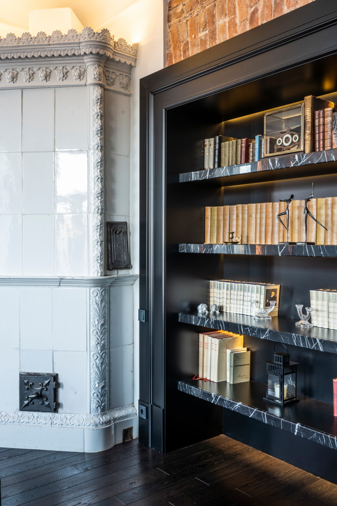 Geräumige Industrial Bibliothek mit schwarzer Wandfarbe, dunklem Holzboden, Eckkamin, gefliester Kaminumrandung, TV-Wand, freigelegten Dachbalken und Ziegelwänden in Sankt Petersburg