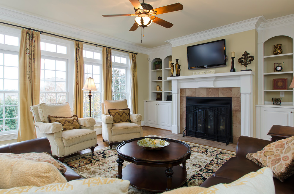 This is an example of a mid-sized traditional formal living room in Raleigh with beige walls, medium hardwood floors, a standard fireplace, a tile fireplace surround and a wall-mounted tv.
