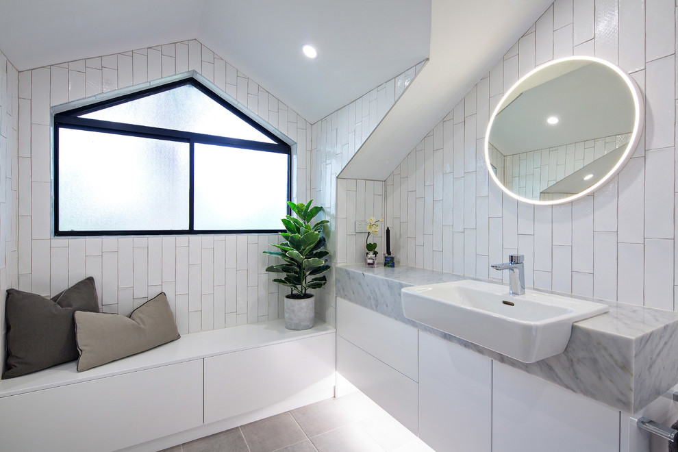Inspiration for a large contemporary master bathroom in Sydney with flat-panel cabinets, white cabinets, a freestanding tub, a curbless shower, a one-piece toilet, white tile, ceramic tile, white walls, ceramic floors, a drop-in sink, marble benchtops, grey floor and a hinged shower door.