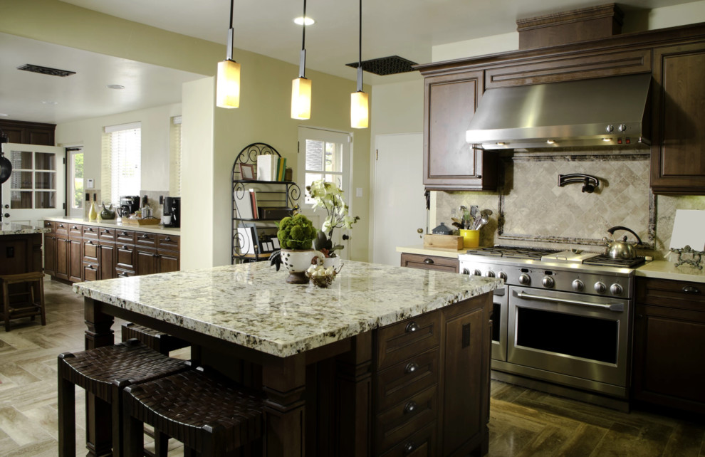 Open concept kitchen - mid-sized transitional medium tone wood floor and brown floor open concept kitchen idea with raised-panel cabinets, dark wood cabinets, granite countertops, beige backsplash, stainless steel appliances, an island and gray countertops