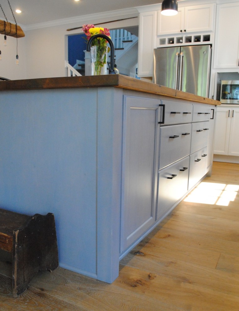 Inspiration for a transitional light wood floor eat-in kitchen remodel in Baltimore with a farmhouse sink, flat-panel cabinets, white cabinets, quartz countertops, white backsplash, stone tile backsplash, stainless steel appliances and an island