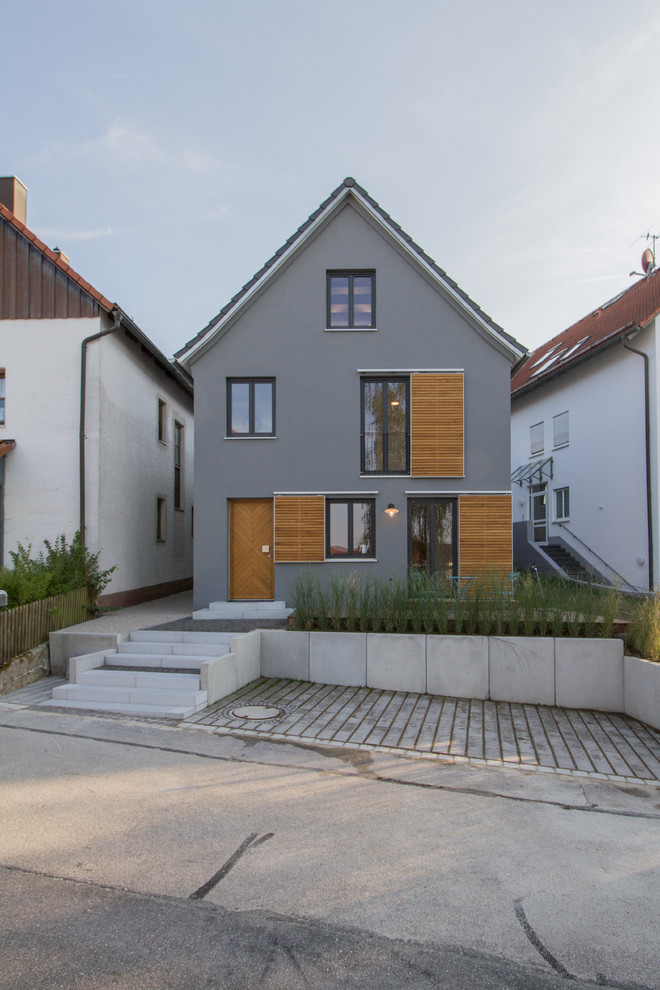 Photo of a mid-sized scandinavian three-storey stucco grey house exterior in Munich with a gable roof.