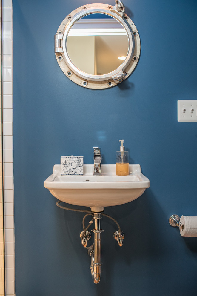 Inspiration for a large country kids bathroom in DC Metro with an alcove shower, a two-piece toilet, white tile, ceramic tile, blue walls, medium hardwood floors, a wall-mount sink and brown floor.
