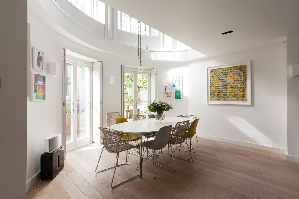 This is an example of a transitional dining room in London with white walls, medium hardwood floors and brown floor.