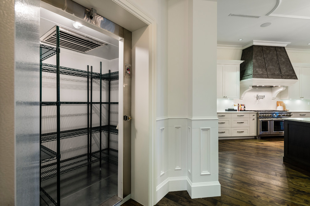 Example of a huge mountain style u-shaped medium tone wood floor and brown floor open concept kitchen design in Vancouver with an undermount sink, shaker cabinets, white cabinets, solid surface countertops, white backsplash, stone slab backsplash, stainless steel appliances, an island and white countertops