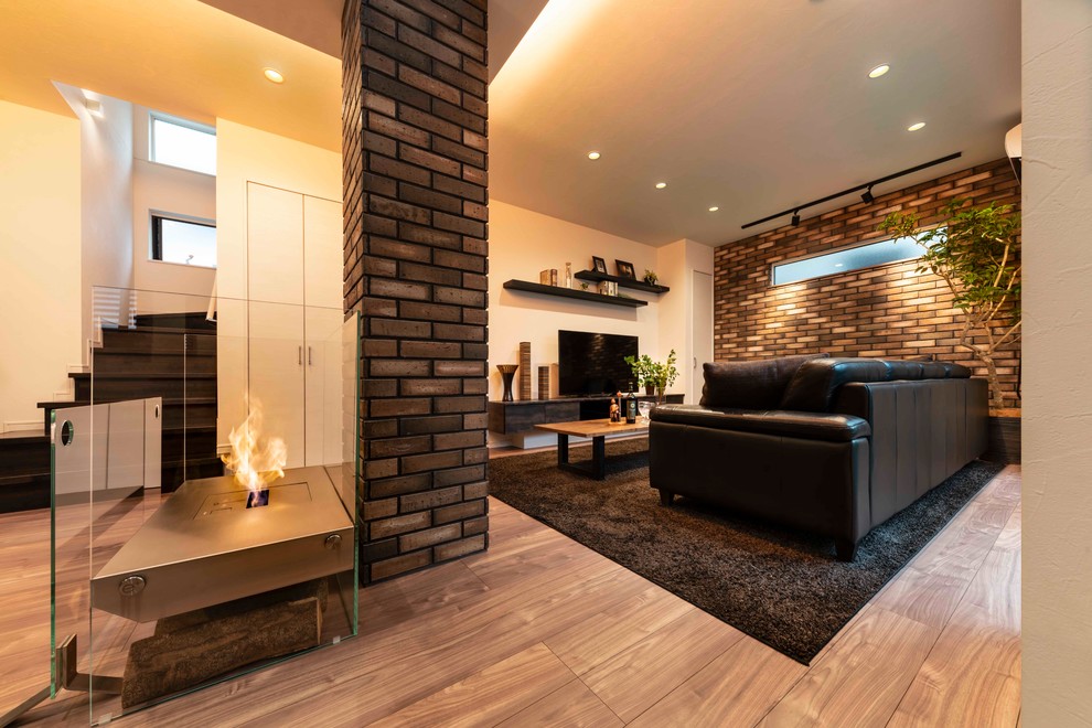 This is an example of a mid-sized modern formal open concept living room in Tokyo with brown walls, plywood floors, a two-sided fireplace, a wood fireplace surround, a freestanding tv and brown floor.