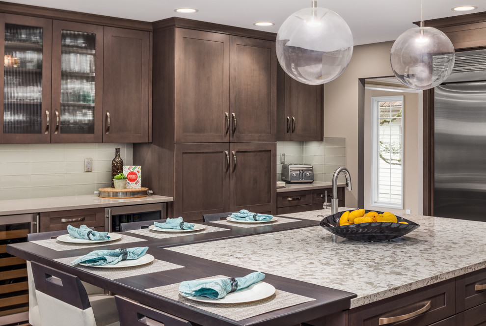 Inspiration for a large transitional u-shaped medium tone wood floor and brown floor eat-in kitchen remodel in Seattle with a single-bowl sink, shaker cabinets, dark wood cabinets, quartzite countertops, gray backsplash, glass tile backsplash, stainless steel appliances, an island and white countertops