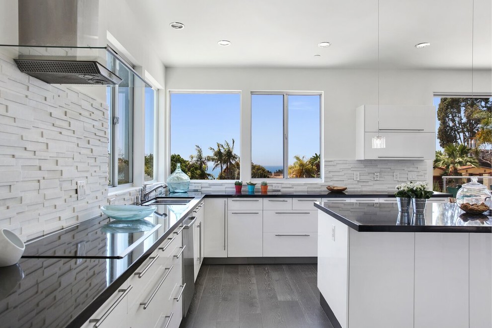 This is an example of a mid-sized contemporary u-shaped eat-in kitchen in Orange County with an undermount sink, flat-panel cabinets, white cabinets, white splashback, stone tile splashback, stainless steel appliances, with island, dark hardwood floors, quartz benchtops, grey floor and grey benchtop.