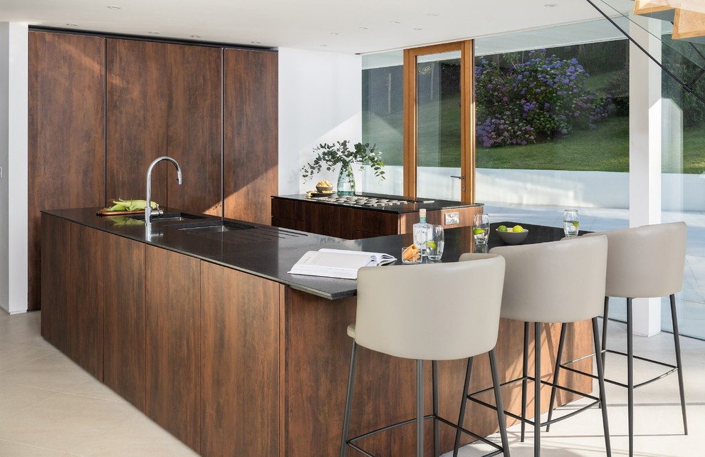 Inspiration for a mid-sized contemporary u-shaped kitchen in Cornwall with flat-panel cabinets, dark wood cabinets, beige floor, black benchtop, a double-bowl sink and multiple islands.