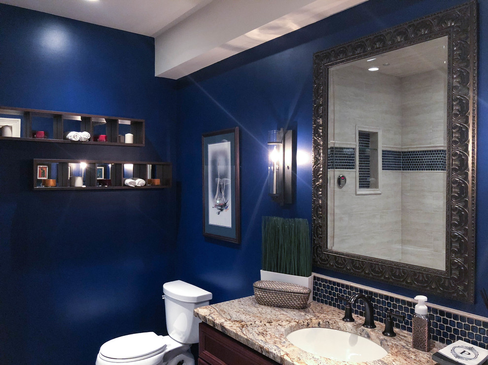 This is an example of an expansive traditional 3/4 bathroom in Philadelphia with furniture-like cabinets, brown cabinets, a corner shower, a one-piece toilet, gray tile, mosaic tile, blue walls, a console sink, engineered quartz benchtops, a hinged shower door and multi-coloured benchtops.