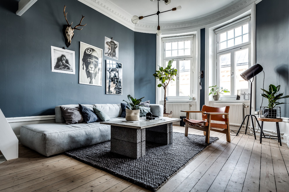 Design ideas for a scandinavian living room in Stockholm with black walls and light hardwood floors.