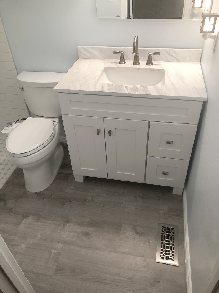 This is an example of a small traditional master bathroom in Seattle with recessed-panel cabinets, white cabinets, a curbless shower, a bidet, white tile, subway tile, white walls, vinyl floors, an integrated sink, marble benchtops, grey floor, a shower curtain, white benchtops, a niche, a single vanity and a freestanding vanity.