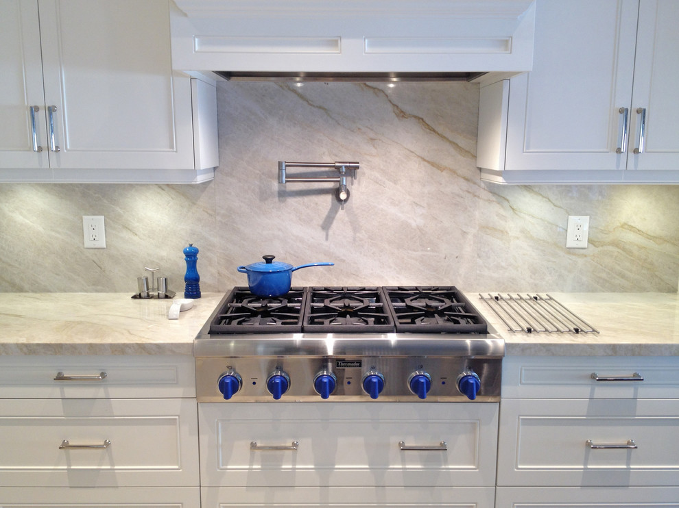 Inspiration for a mid-sized transitional porcelain tile kitchen remodel in Toronto with an undermount sink, recessed-panel cabinets, white cabinets, marble countertops, beige backsplash, marble backsplash, stainless steel appliances, an island and white countertops