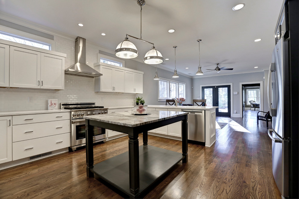 Photo of a large transitional l-shaped eat-in kitchen in Atlanta with medium hardwood floors, an undermount sink, white splashback, subway tile splashback, stainless steel appliances, shaker cabinets, white cabinets, quartz benchtops and with island.