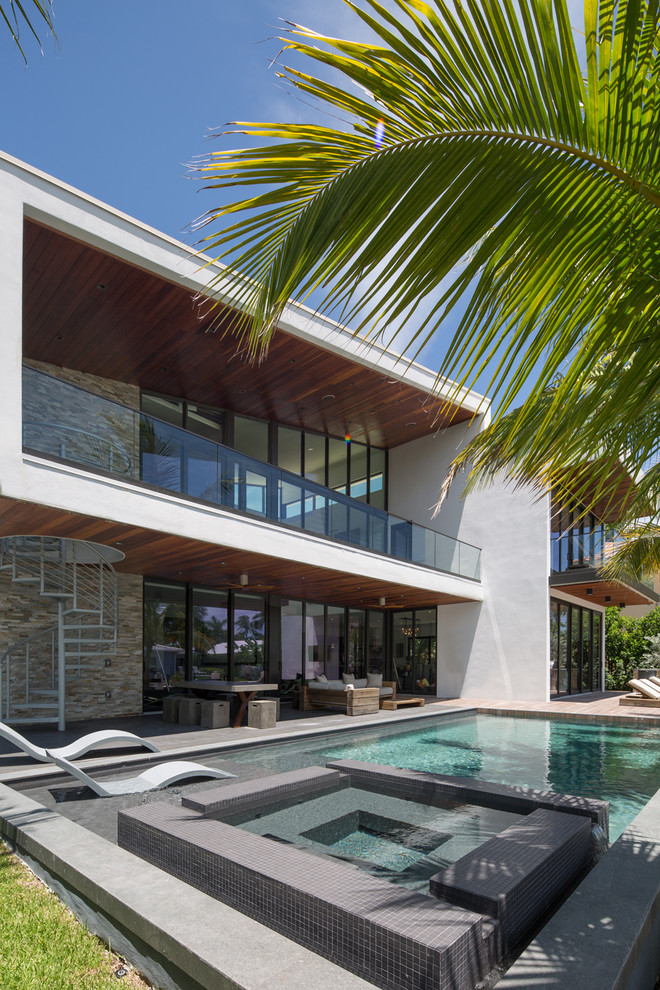 This is an example of a large contemporary backyard rectangular lap pool in Miami with decking.