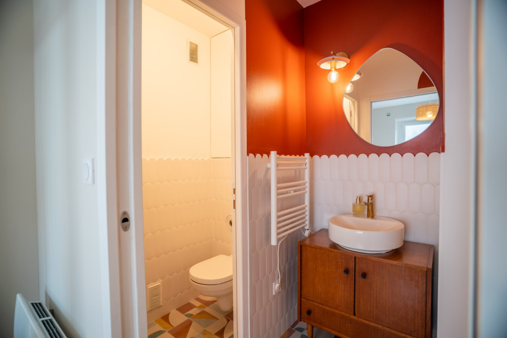 Idées déco pour une petite salle de bain rétro avec WC suspendus, un carrelage blanc, des carreaux de céramique, un mur rouge, carreaux de ciment au sol, un lavabo posé, un plan de toilette en bois, un sol multicolore, une cabine de douche à porte battante, du carrelage bicolore et meuble simple vasque.
