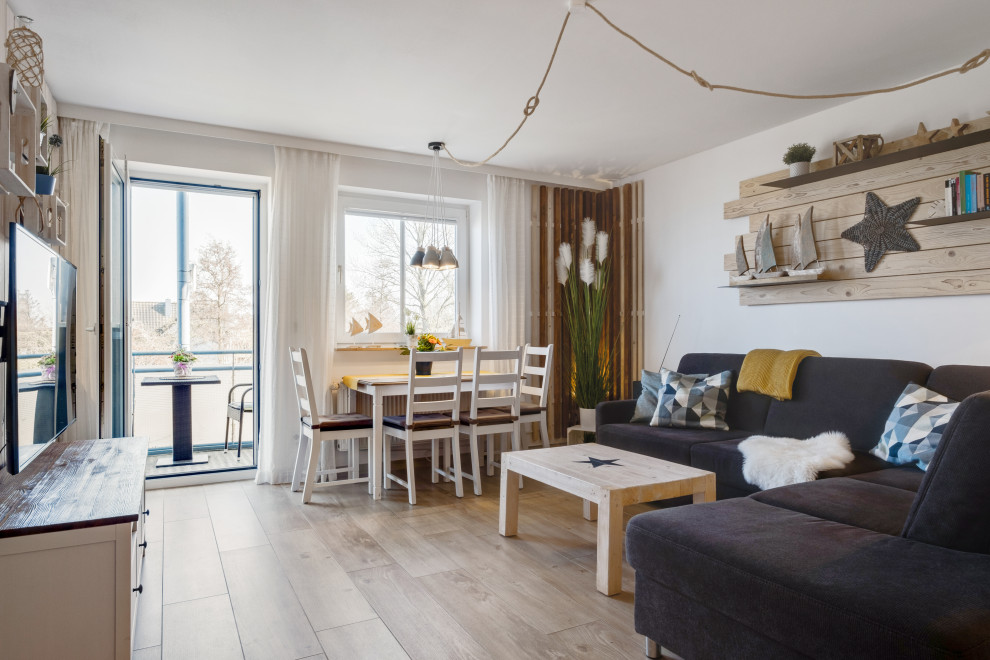 Offenes Maritimes Wohnzimmer mit weißer Wandfarbe, hellem Holzboden und beigem Boden in Sonstige