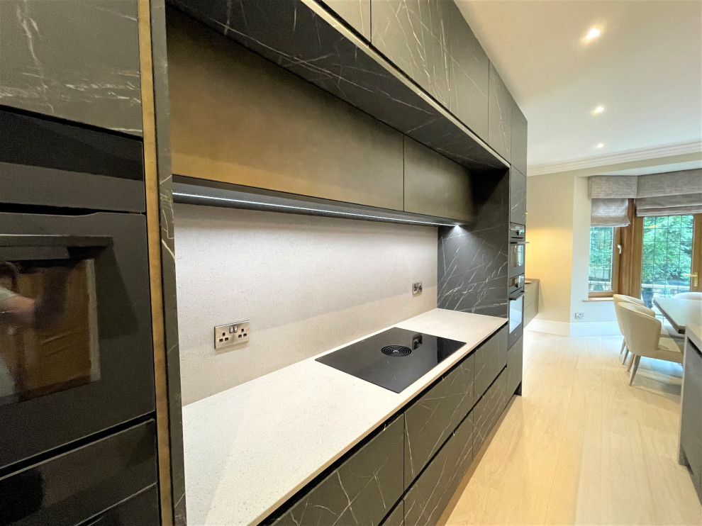 Large contemporary l-shaped eat-in kitchen in Other with a single-bowl sink, flat-panel cabinets, black cabinets, solid surface benchtops, black appliances, porcelain floors and with island.