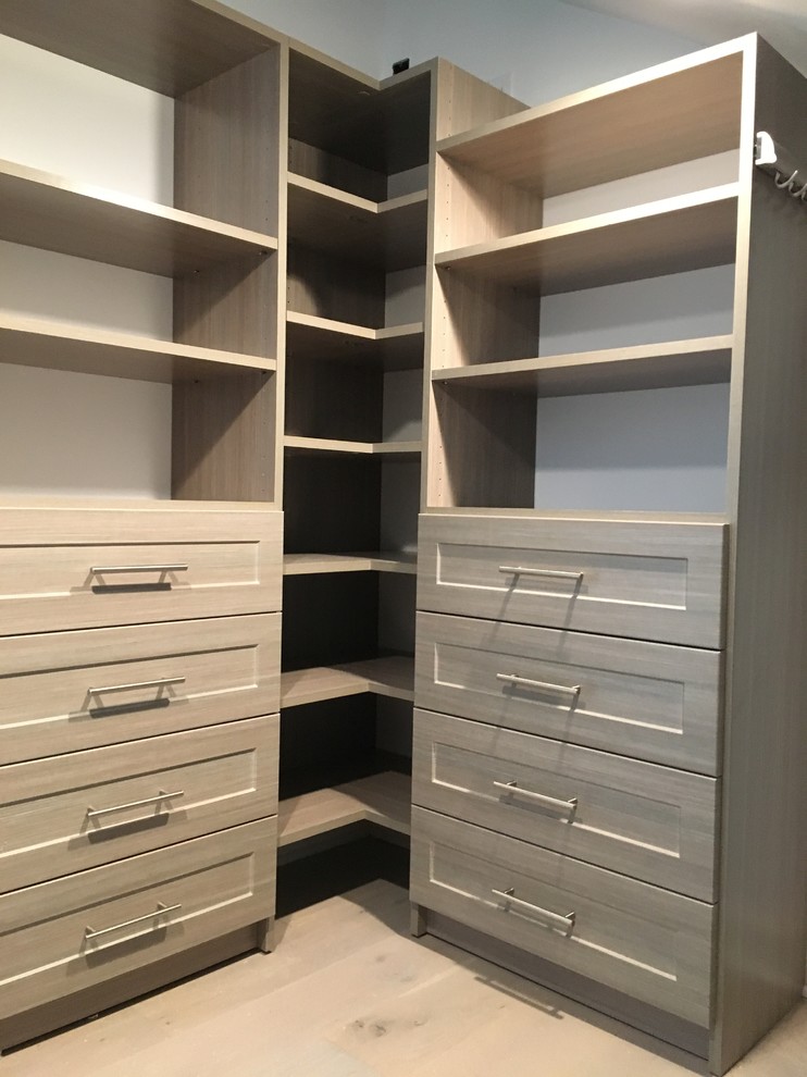Photo of a mid-sized transitional gender-neutral dressing room in New York with shaker cabinets, distressed cabinets and medium hardwood floors.