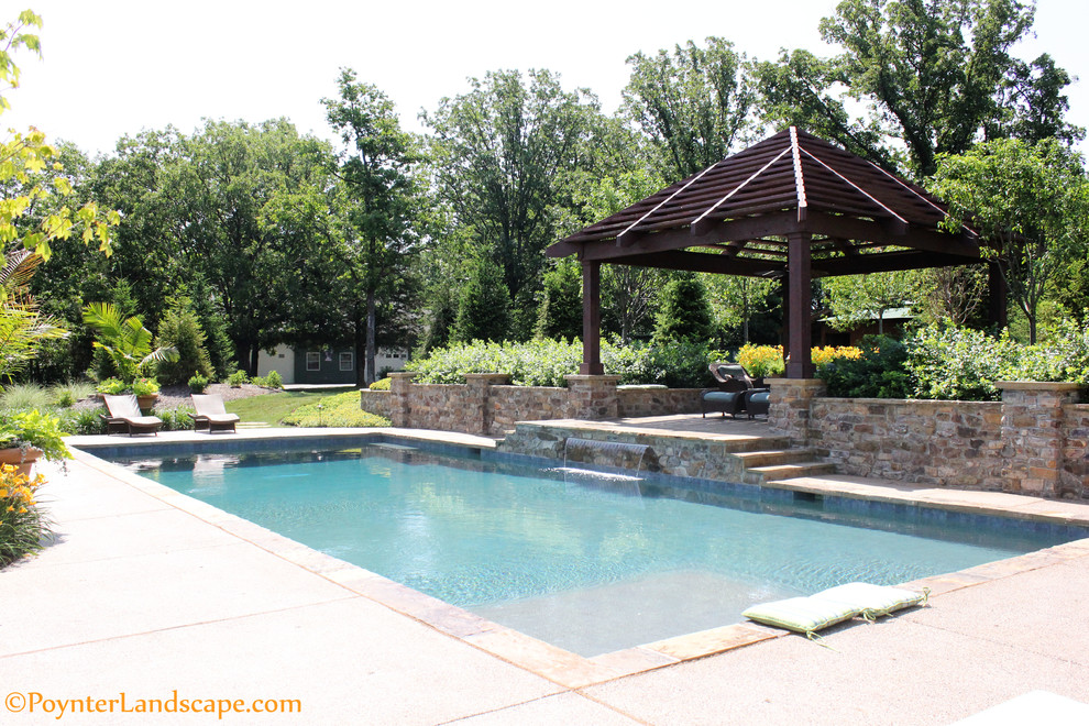 Large country backyard rectangular natural pool in St Louis with a water feature and concrete slab.