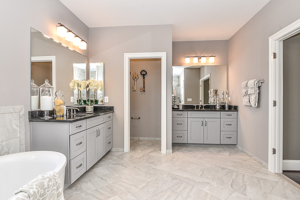 This is an example of a mid-sized transitional 3/4 bathroom in DC Metro with shaker cabinets, grey cabinets, a freestanding tub, an alcove shower, a two-piece toilet, gray tile, porcelain tile, multi-coloured walls, porcelain floors, an undermount sink and quartzite benchtops.