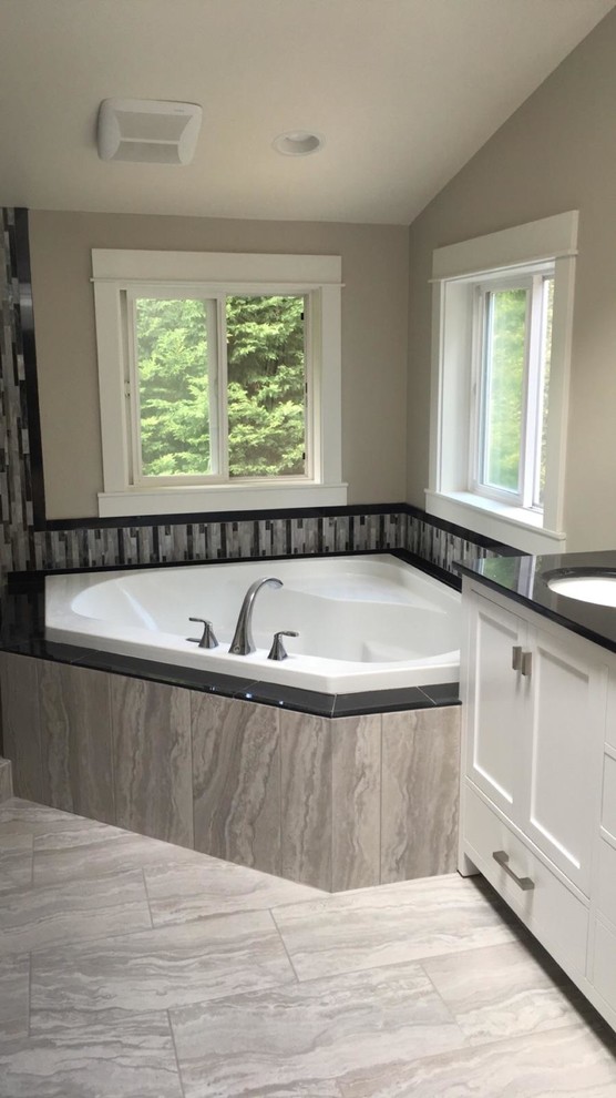 Large contemporary master bathroom in Seattle with shaker cabinets, white cabinets, a corner tub, an alcove shower, a two-piece toilet, black and white tile, mosaic tile, beige walls, porcelain floors, an undermount sink and granite benchtops.