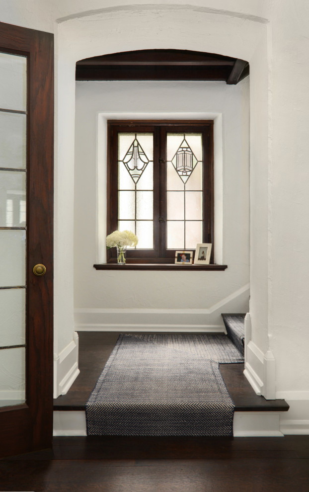 Cette photo montre une entrée chic de taille moyenne avec un couloir, un mur blanc, parquet foncé, une porte simple, une porte en bois foncé, un sol marron et poutres apparentes.
