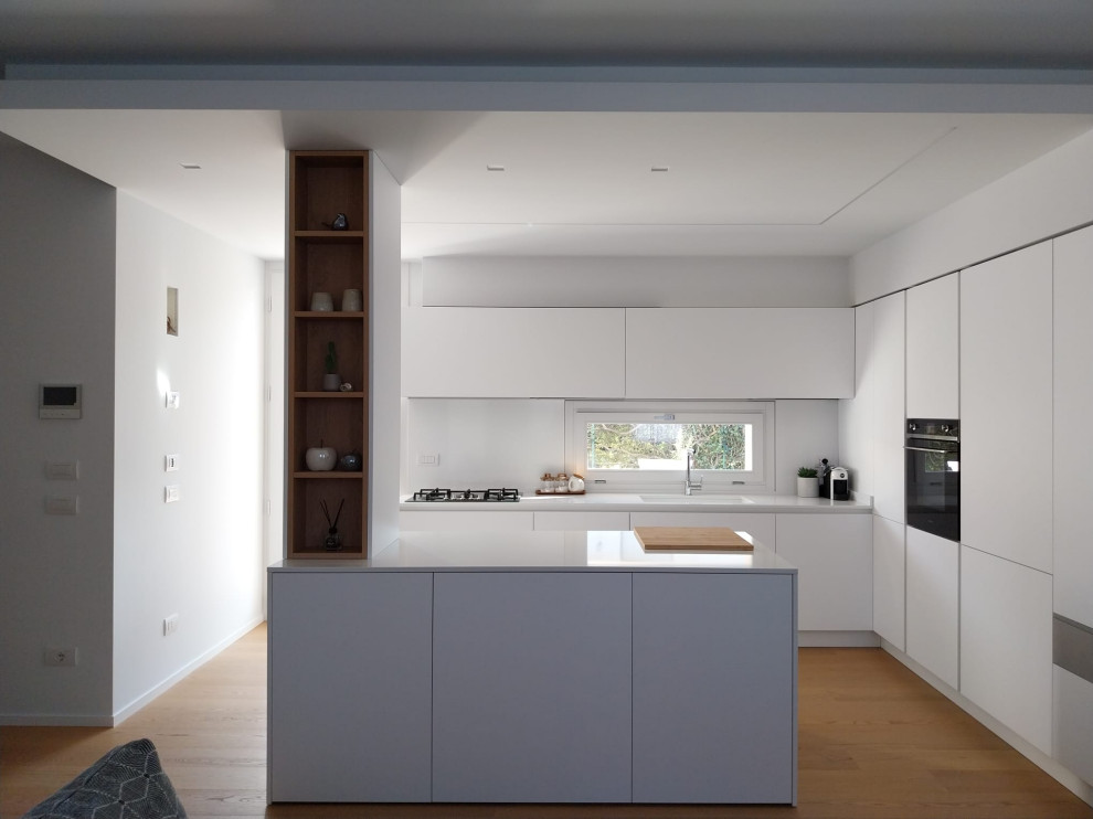 Inspiration for a mid-sized modern u-shaped eat-in kitchen in Other with an undermount sink, flat-panel cabinets, white cabinets, quartz benchtops, white splashback, black appliances, with island, white benchtop and recessed.