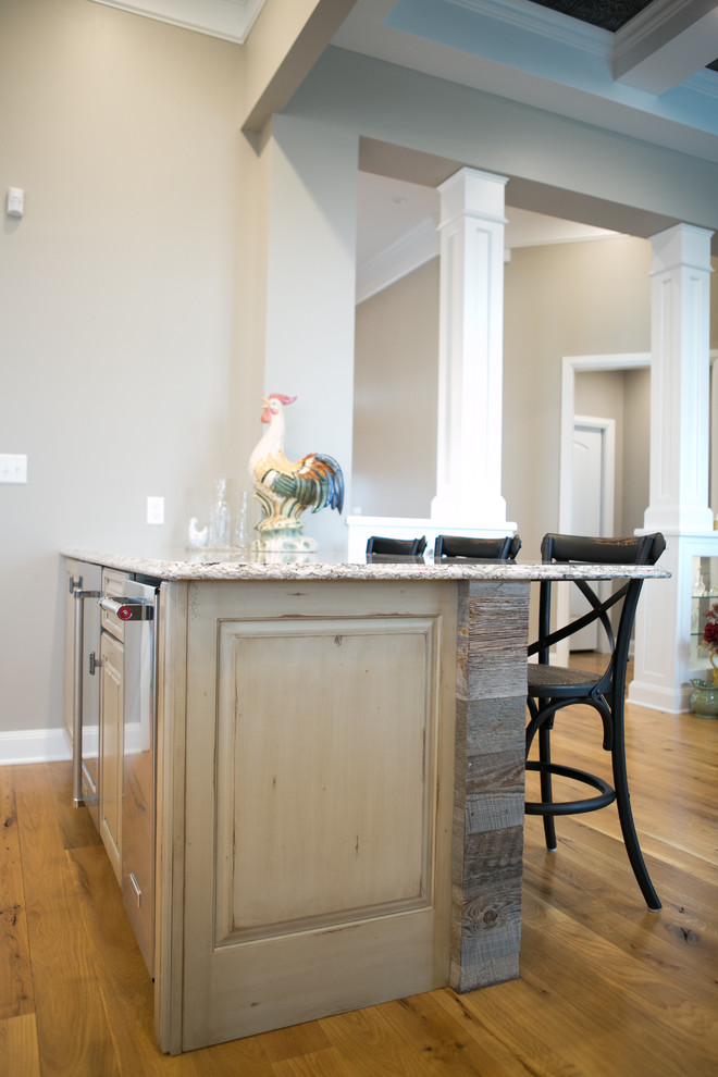 Kitchen - large transitional u-shaped medium tone wood floor and brown floor kitchen idea in Indianapolis with a farmhouse sink, raised-panel cabinets, dark wood cabinets, granite countertops, white backsplash, subway tile backsplash, paneled appliances, an island and multicolored countertops
