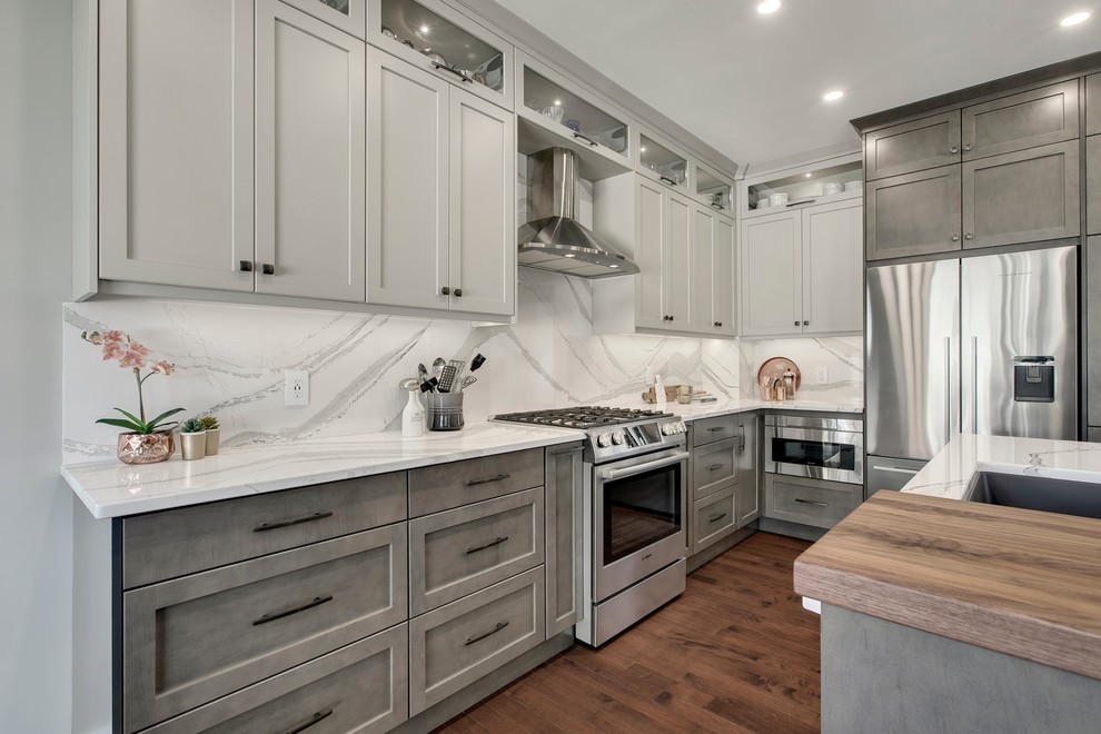 Design ideas for a large transitional u-shaped eat-in kitchen in Calgary with an undermount sink, recessed-panel cabinets, grey cabinets, quartzite benchtops, white splashback, stone slab splashback, stainless steel appliances, dark hardwood floors, with island, brown floor and white benchtop.