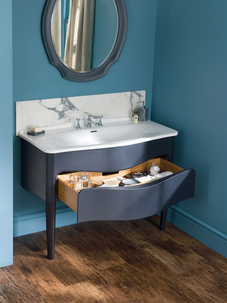 This is an example of a small traditional 3/4 bathroom in Other with flat-panel cabinets, blue cabinets, blue walls, dark hardwood floors, an integrated sink and brown floor.