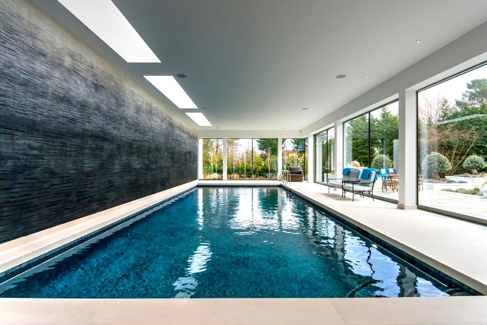 Design ideas for a mid-sized contemporary indoor rectangular lap pool in Surrey with natural stone pavers.