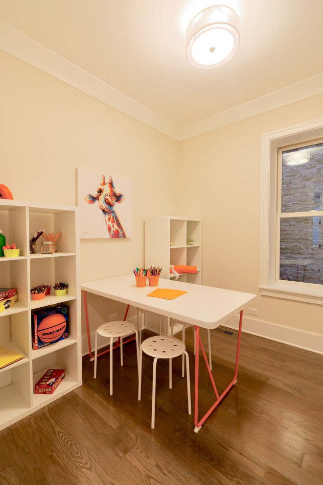 This is an example of a small transitional gender-neutral kids' study room for kids 4-10 years old in Chicago with beige walls, medium hardwood floors and brown floor.