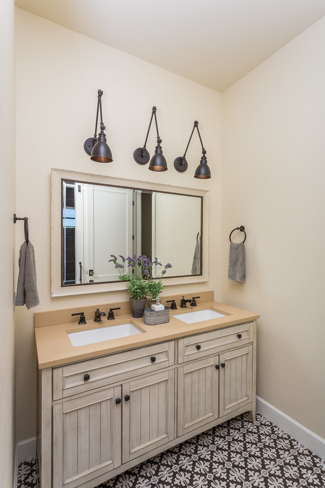 This is an example of a mid-sized country bathroom in Phoenix with furniture-like cabinets, beige cabinets, beige walls, porcelain floors, an undermount sink, engineered quartz benchtops, brown floor and beige benchtops.